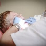 A young boy receiving a dental examination by a professional dentist in a clinic setting.