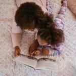 A mother and daughter enjoying storytime on a cozy bed, fostering bonding and togetherness.