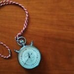 Close-up shot of an antique stopwatch with rope on wooden table.