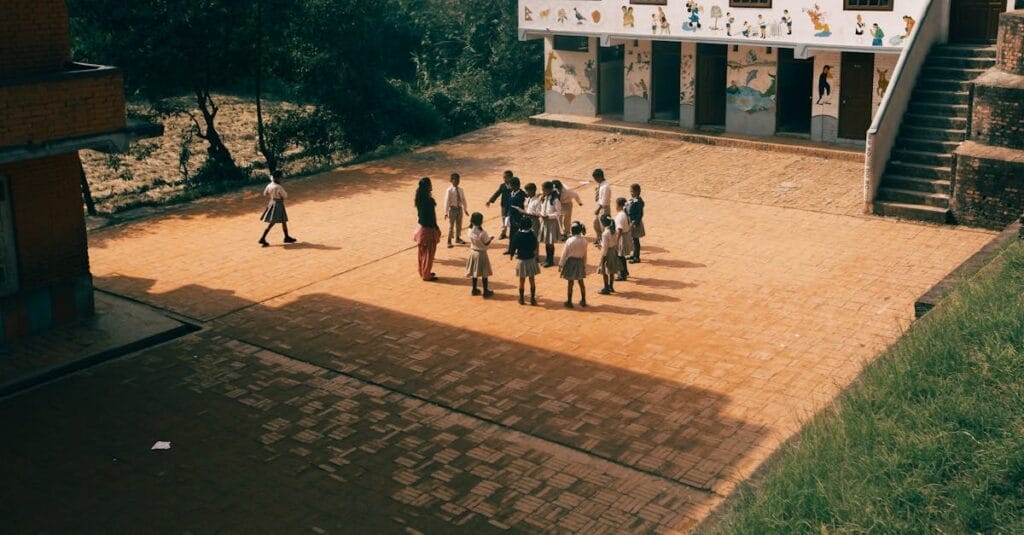 Group of children playing together on a sunny day in a school yard with murals outside.
