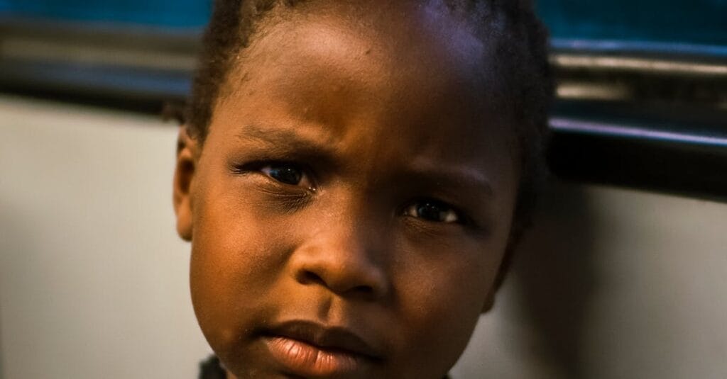 Close-up portrait of an African American girl with a thoughtful expression, captured indoors.