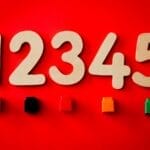 Wooden numbers and colored blocks on a vibrant red background, ideal for educational themes.