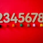 Wooden numbers with colorful cubes on a vibrant red background.