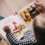 A child and adult reading an illustrated storybook together in a cozy setting.