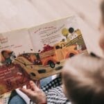 A mother and toddler sharing a story from an illustrated children's book indoors.