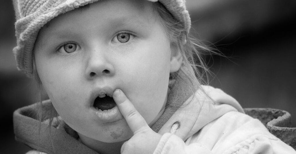 A captivating black and white close-up portrait of a young girl in a knitted hat.