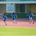 Boys running on a track during a sunny day in New Territories, Hong Kong.