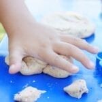 Young child having fun playing with colorful clay at an outdoor table.