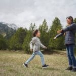 A joyful moment between mother and child in the mountains, surrounded by greenery.