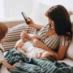 A mother relaxes on a sofa with her two children, enjoying quality time together.