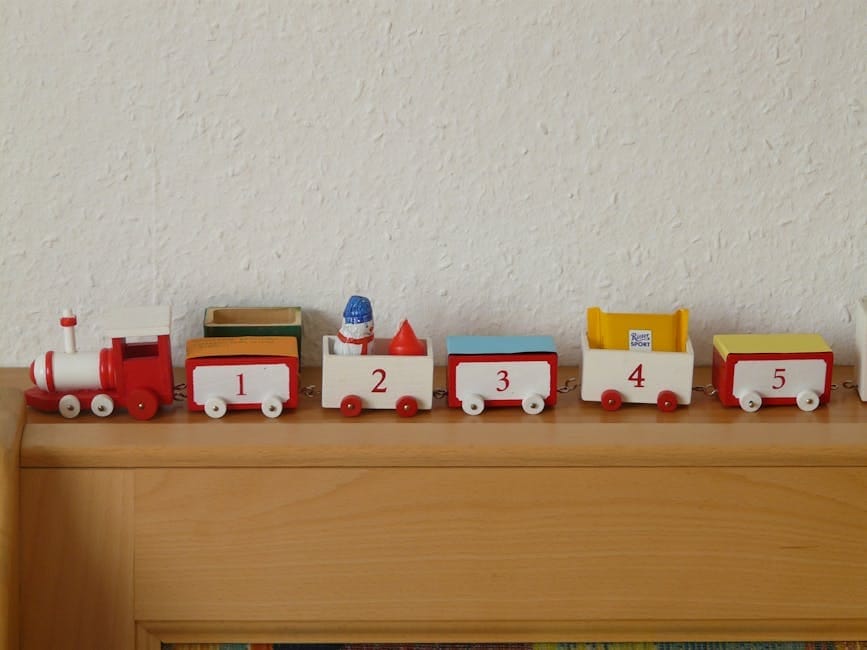 Red and white wooden toy train with numbers displayed on a wooden shelf.