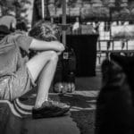 A child sitting alone on a curb, depicting solitude and contemplation in a monochrome city setting.