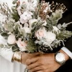 Close-up of a wedding bouquet held by bride and groom, showcasing romance and elegance.