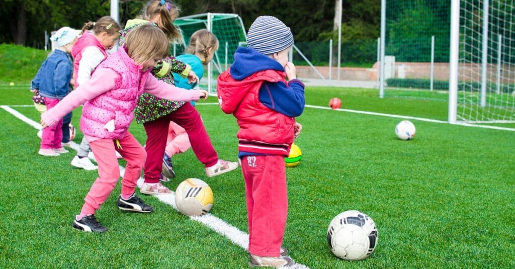 Kids having fun playing soccer outdoors on a sunny day in a park.