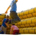 Kids enjoying a fun time bouncing in a vibrant inflatable castle outdoors.