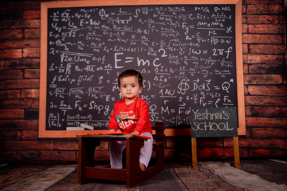 Cute baby in a classroom setting with a large chalkboard filled with equations.