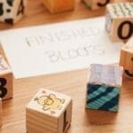 Colorful wooden alphabet and number blocks arranged on a table with 'Finished Blocks' sign.