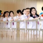 A joyful group of students in uniforms holding colorful pinwheels, standing in line.