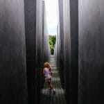 A young girl runs playfully through the narrow pathways of a modern concrete monument.