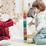 Two young children enjoying playtime with wooden blocks in a cozy indoor setting, fostering creativity and fun.