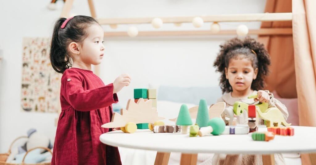 Two children engaging with wooden toys in a bright playroom. Ideal for education themes.