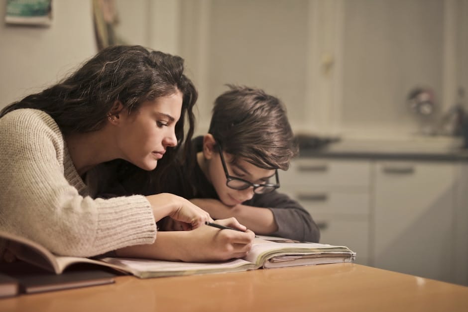 An attentive girl helps her younger brother concentrate on homework in a cozy home setting.