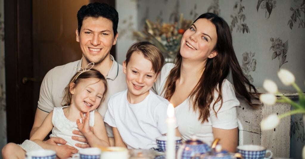 Cheerful family of four enjoying a warm and cozy teatime at home, surrounded by love and laughter.