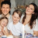 Cheerful family of four enjoying a warm and cozy teatime at home, surrounded by love and laughter.