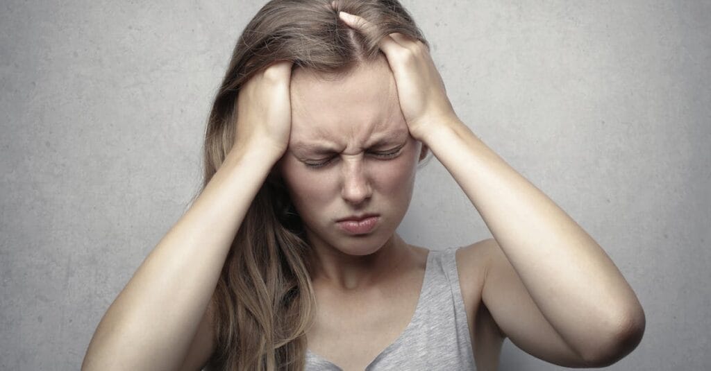 Young woman expressing stress and frustration while holding her head.