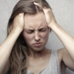 Young woman expressing stress and frustration while holding her head.