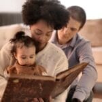 Mother, father, and child enjoying a storybook together in their cozy living room.