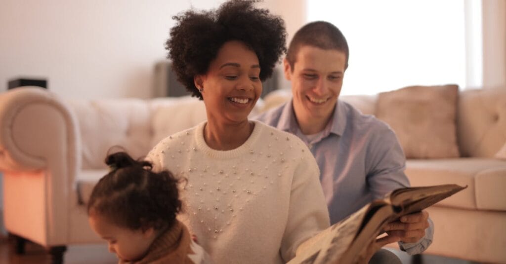 A family shares joyful moments reading a storybook indoors, creating cherished memories.