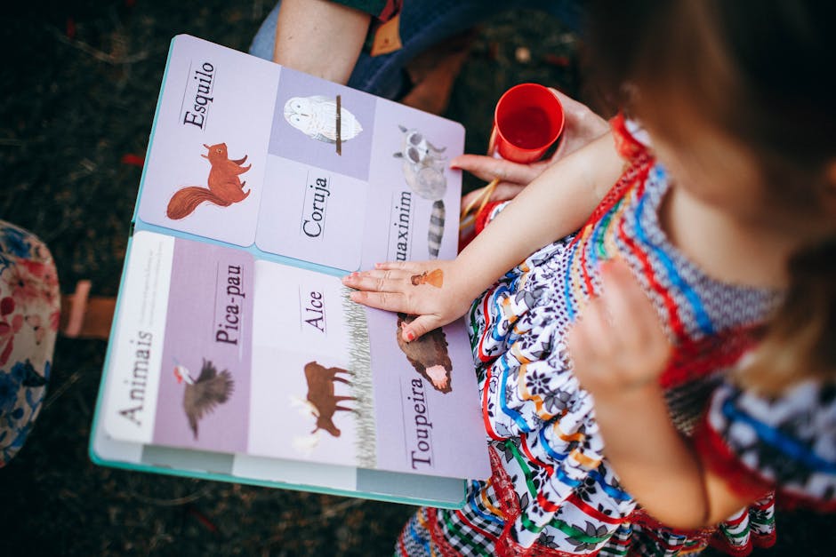 Young girl reading a colorful animal picture book outdoors, enjoying a sunny day in the park.