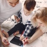 Parents and child enjoying drawing together on the floor, creating memories.