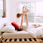 A father and daughter enjoying playful bonding time on a sunny morning in a cozy bedroom.