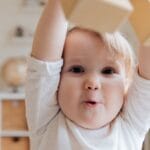 Adorable baby enjoying playtime with wooden blocks in a cozy indoor setting. Perfect depiction of joy and learning.