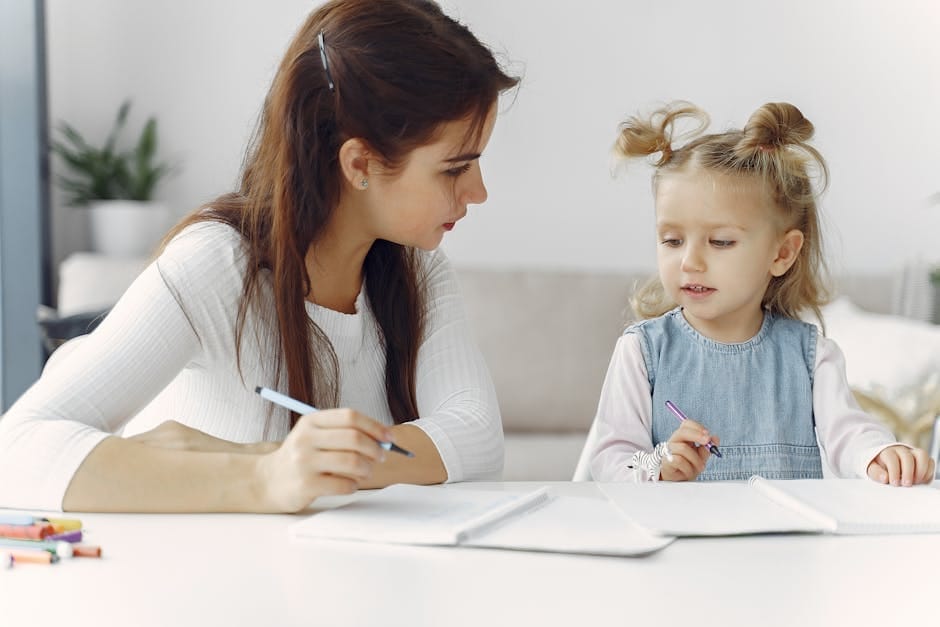 A mother and daughter enjoy quality time together coloring at a table indoors.