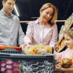 A joyful family of three shopping together in a supermarket, creating a memorable experience.