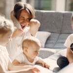 Woman going mad while sitting with little kids playing together on sofa in well lit room