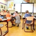 Children engaged in learning with a teacher in a bright classroom setting.