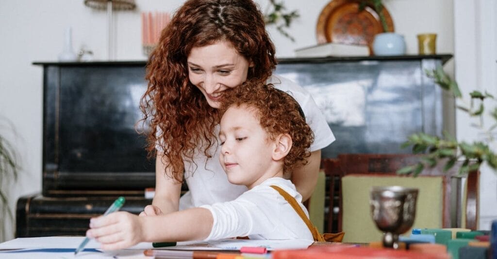 A loving mother and her child enjoy drawing together at home, fostering creativity and family bonding.
