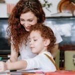 A loving mother and her child enjoy drawing together at home, fostering creativity and family bonding.