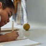 A young girl concentrating on homework at home using a tablet.