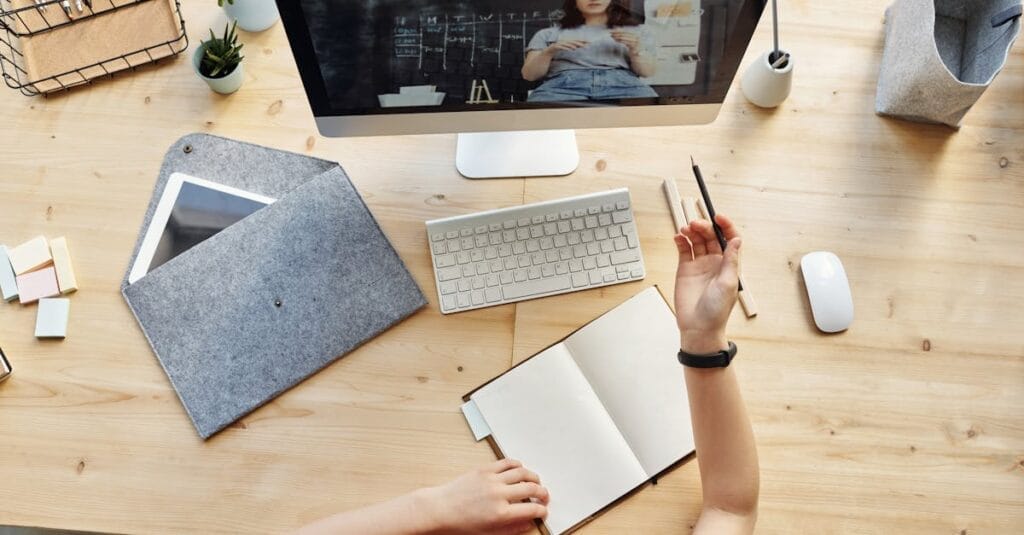 Teen girl actively learning in an organized home workspace via online class on a desktop computer.