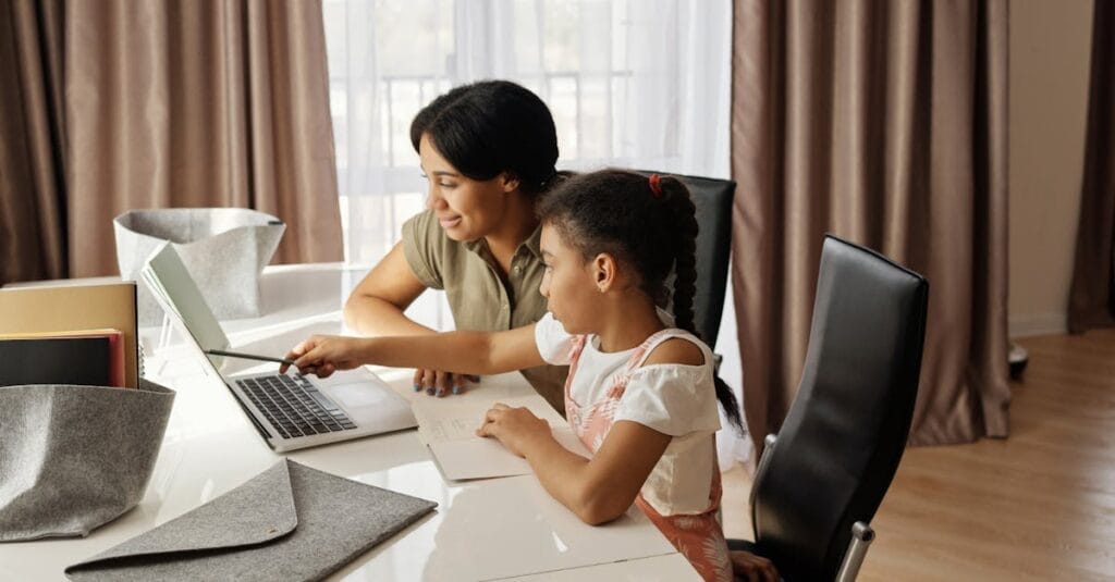 A mother assisting her daughter with online learning on a laptop, promoting education and family bonding.