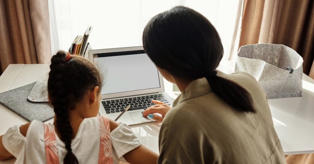 A mother helps her daughter with online learning on a laptop at home, emphasizing family education.