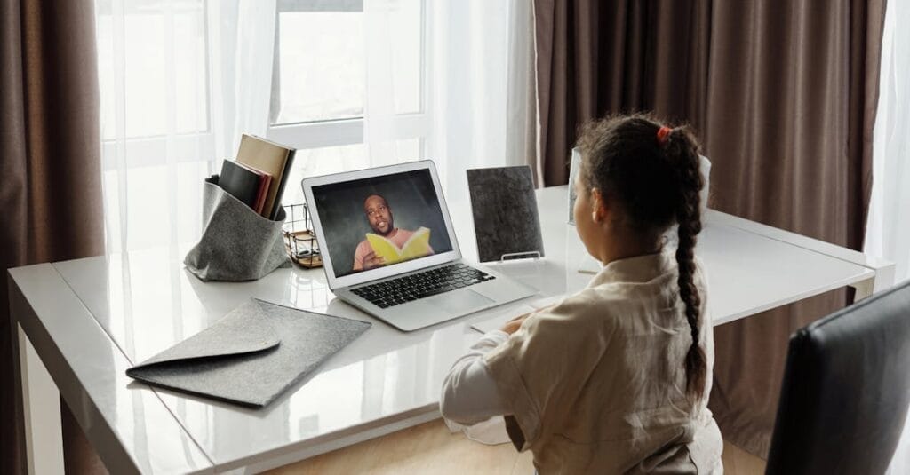 Young girl engaged in a virtual learning session at home with a teacher on video call.