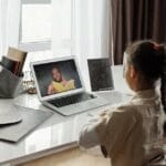 Young girl engaged in a virtual learning session at home with a teacher on video call.