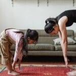 A mother and daughter practicing yoga in a cozy living room, promoting fitness and bonding.