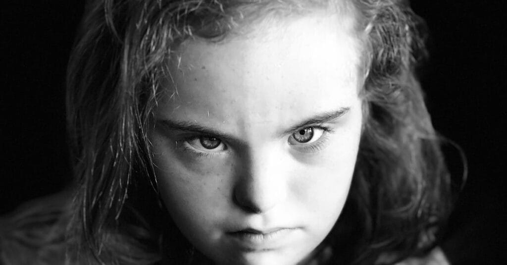 Captivating close-up black and white portrait of a young girl with intense gaze.